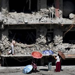 Unas personas observan una casa dañada por la repentina inundación en Trishuli, en el distrito nepalí de Nuwakot. La catastrófica inundación del 26 de agosto fue provocada por el colapso de un glaciar en la cordillera del Himalaya, en la frontera entre China y Nepal, un fenómeno que los científicos han vinculado al cambio climático. Las aguas, que avanzaron con la fuerza de un tsunami, arrasaron distritos montañosos, destruyendo carreteras, puentes y presas hidroeléctricas, y causaron la muerte de al menos 1.446 personas. | Foto:PRAKASH MATHEMA / AFP