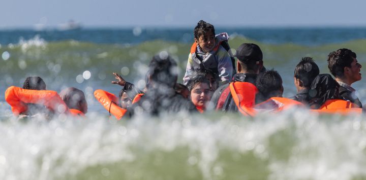 Un grupo de migrantes intenta subir a una embarcación de traficantes frente a la playa de Equihen-Plage, en el norte de Francia. El cuerpo de un hombre fue hallado en la playa de Neufchatel-Hardelot (Pas-de-Calais), poco después de un intento de partida de migrantes hacia Inglaterra, según observaron periodistas de la AFP.