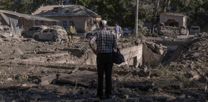 Una persona se encuentra junto a vehículos y edificios dañados por un ataque ruso en Kiev, que también alcanzó un hospital cercano, en el marco de la invasión rusa de Ucrania. Rusia está intensificando su invasión de Ucrania, que dura ya cuatro años y medio, mediante ataques letales con misiles balísticos, según declaró el presidente ucraniano Volodímir Zelenski, quien instó a una respuesta global tras un ataque nocturno ruso que causó al menos 13 muertos.