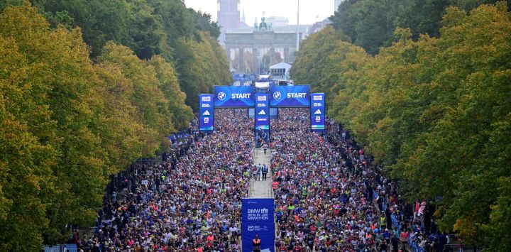 Los corredores toman la salida de la 52.ª edición del Maratón de Berlín en Berlín, Alemania, con el Ayuntamiento Rojo y la Puerta de Brandeburgo visibles al fondo.