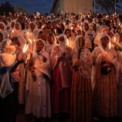Los creyentes ortodoxos etíopes vestidos con ropa blanca tradicional sostienen velas encendidas al atardecer durante las celebraciones de Meskel en la Plaza Meskel en Addis Abeba. La celebración etíope de Meskel es una fiesta religiosa anual en la iglesia ortodoxa etíope que conmemora el descubrimiento de la Verdadera Cruz en el siglo IV por la emperatriz romana Helena. | Foto:Solan Kolli / AFP
