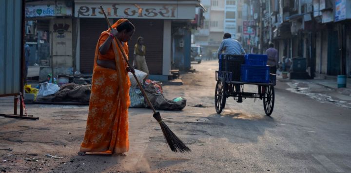 Una mujer barre una calle en Ahmedabad, India.