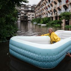 Un hombre arrastra a una mujer en una balsa inflable a través de las aguas de la inundación en el distrito de Bang Kapi, en Bangkok. Miles de residentes de Bangkok amanecieron en refugios después de que las inundaciones, provocadas por días de fuertes lluvias en la capital tailandesa, anegaran viviendas y carreteras; algunos ya han comenzado a secar sus hogares y pertenencias. | Foto:Chanakarn Laosarakham / AFP