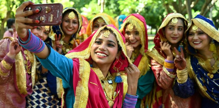 Estudiantes vestidas con trajes tradicionales punjabíes se toman selfis tras su actuación en el concurso de danza folclórica "Giddha" en una universidad de Amritsar, India.