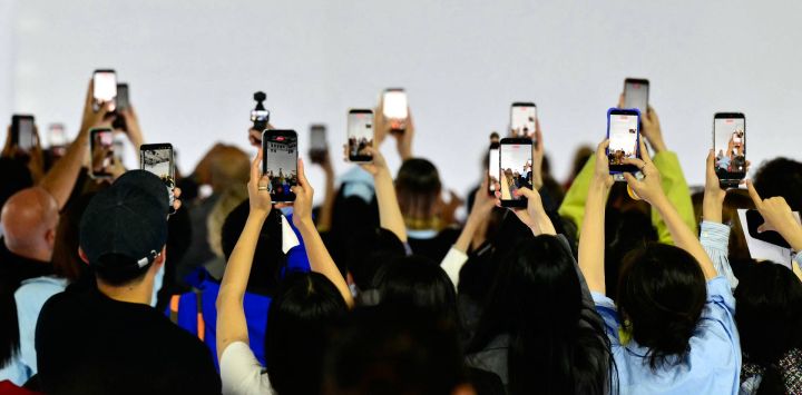 Los asistentes sostienen sus teléfonos inteligentes durante el desfile de la colección de Prada, en el marco de la Semana de la Moda de Milán, temporada Primavera/Verano 2027 para mujer.
