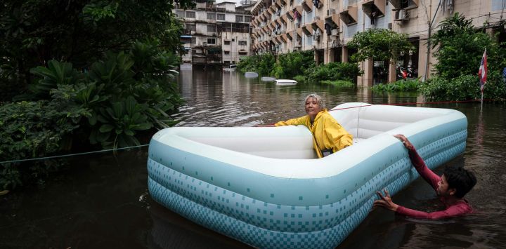 Un hombre arrastra a una mujer en una balsa inflable a través de las aguas de la inundación en el distrito de Bang Kapi, en Bangkok. Miles de residentes de Bangkok amanecieron en refugios después de que las inundaciones, provocadas por días de fuertes lluvias en la capital tailandesa, anegaran viviendas y carreteras; algunos ya han comenzado a secar sus hogares y pertenencias.