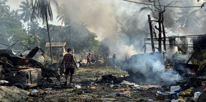 Personas caminan entre el humo y los escombros humeantes tras un ataque aéreo militar contra un mercado y un puente adyacente en Kyauktaw, en el oeste del estado de Rakáin. Un ataque aéreo militar contra un mercado en el oeste de Myanmar causó la muerte de 33 personas e hirió a otras 36, según informó en un comunicado una facción rebelde que controla la zona.