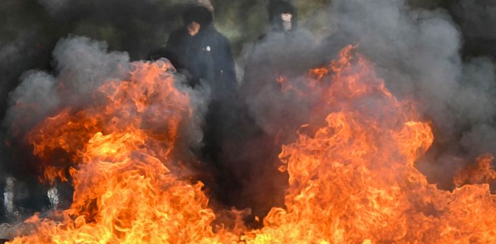 Estudiantes que protestan permanecen frente a una barricada quemada durante una acción de bloqueo a las puertas del instituto Le Corbusier, en Aubervilliers (al norte de París). Desde finales de septiembre, los estudiantes han protagonizado protestas frente a los centros educativos por diversas quejas, que van desde los horarios, el tamaño de las clases y la falta de profesores hasta el calor excesivo en las aulas durante las olas de calor de este año.