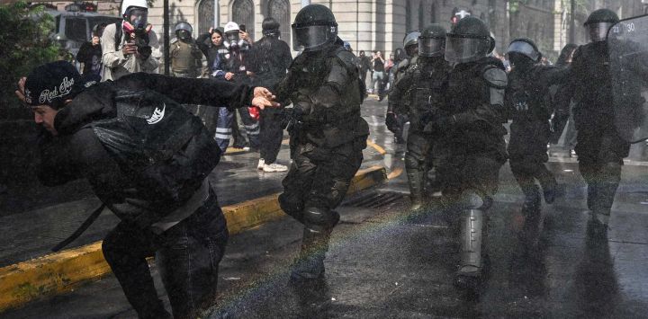 Un manifestante se aleja de oficiales de la policía antimotines durante el paro nacional convocado por la Confederación de Estudiantes de Chile en contra de los eventuales recortes a la educación, en el marco de la discusión de la Ley de Presupuesto 2027, en Santiago, capital de Chile.