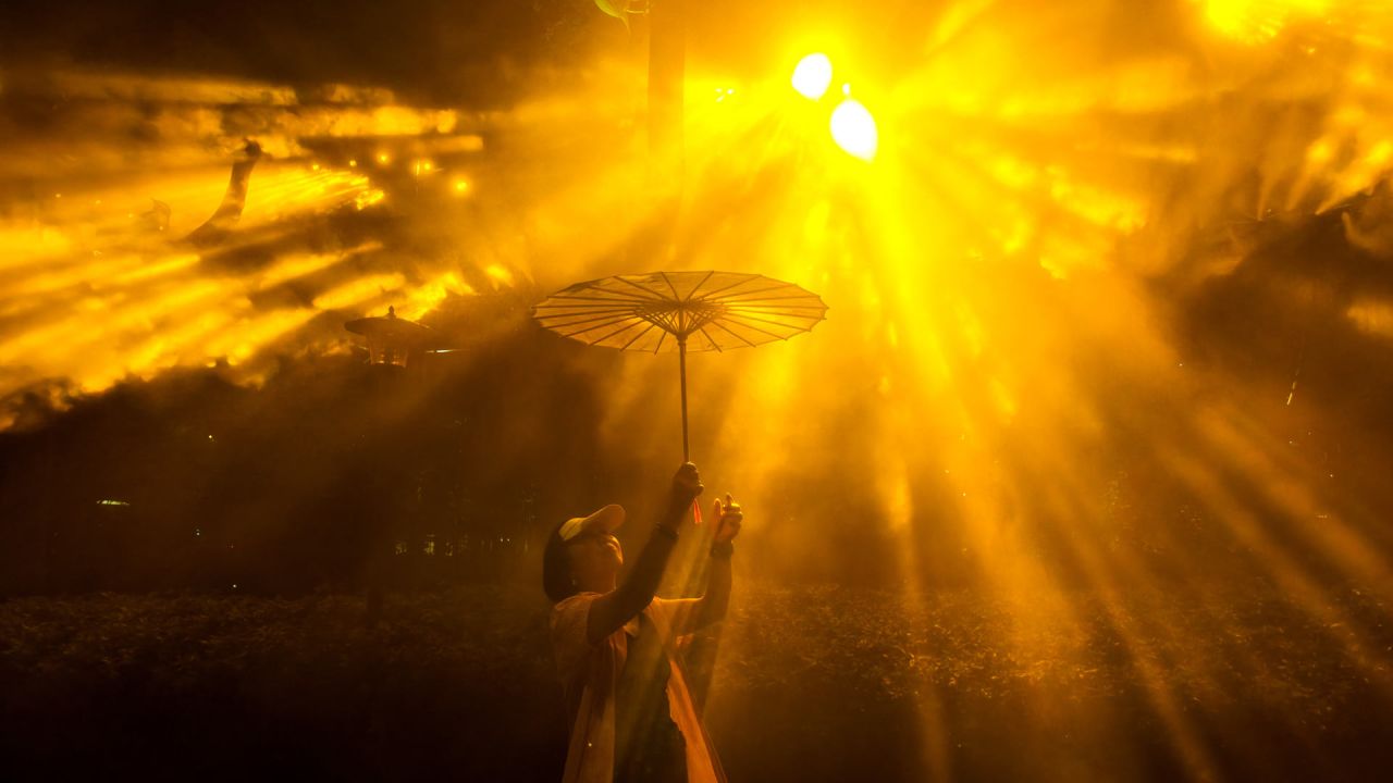 Una mujer que sostiene un paraguas posa para una fotografía mientras visita el Festival Internacional de la Luz de Shanghái, en un parque de la ciudad. | Foto:CN-STR / AFP