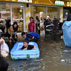 Las familias juegan en las aguas inundadas a lo largo de la carretera Ramkhamhaeng en el distrito de Bang Kapi, Bangkok. Las profundas inundaciones en Bangkok llevaron a miles de residentes a refugios mientras otros se apresuraban a comprar comestibles o secar sus hogares después de días de fuertes lluvias que inundaron mercados, carreteras y residencias. | Foto:LILLIAN SUWANRUMPHA / AFP