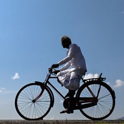 Un hombre recorre en bicicleta la presa del embalse de Ibbankatuwa en Dambulla, Sri Lanka. | Foto:ISHARA S. KODIKARA / AFP