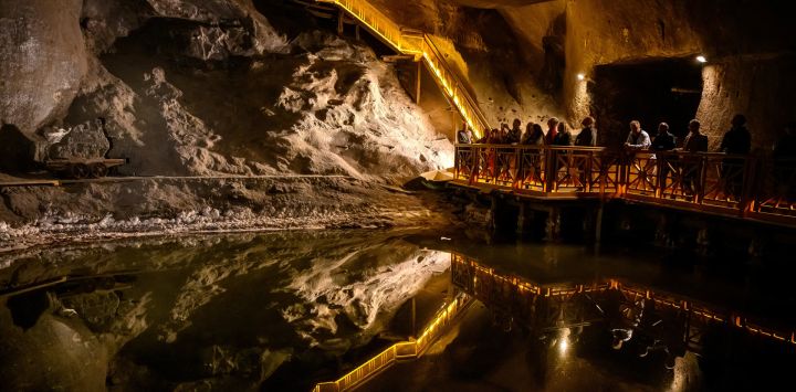 Esta fotografía muestra a turistas visitando un lago subterráneo artificial en la mina de sal de Wieliczka, a las afueras de Cracovia. Wieliczka, una de las minas de sal más antiguas del mundo, está reconocida por la UNESCO como Patrimonio de la Humanidad. Es una atracción turística, pero también un centro de salud que lleva casi 200 años ofreciendo terapia con sal a pacientes con problemas pulmonares.