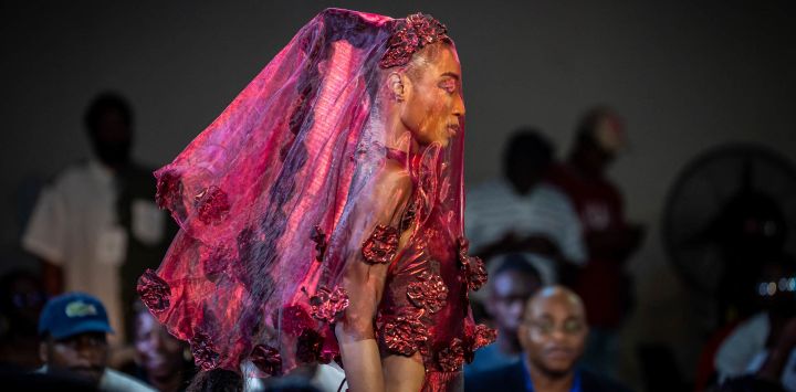 Unas modelos presentan una creación de Wosstika's Design durante la Semana de la Moda de Nigeria 2026, celebrada en el Soul Lounge Resort de Abuya. Las modelos nigerianas lucieron atuendos que incorporaban cantidades de tela aparentemente imposibles, plegadas y moldeadas para formar siluetas voluminosas o superpuestas en patrones que recordaban a las escamas o a las plumas.