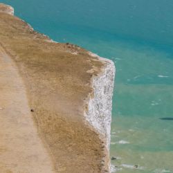 Esta vista aérea muestra a personas caminando sobre hierba completamente seca, a lo largo del borde del acantilado sobre el faro de Beachy Head, cerca de Eastbourne, en la costa sur de Inglaterra. | Foto:Brook Mitchell / AFP