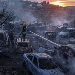 Un bombero de la defensa civil palestina sofoca un incendio que calcinó automóviles y olivos en un depósito de chatarra tras un ataque presuntamente perpetrado por colonos israelíes en la localidad de Ayn Yabrud, al noreste de Ramala, en Cisjordania (territorio ocupado por Israel). La violencia se ha intensificado paralelamente a la ofensiva de Israel en Gaza, iniciada en respuesta al ataque masivo de Hamás del 7 de octubre de 2023. Según las Naciones Unidas, los ataques de colonos israelíes contra palestinos —que incluyen agresiones físicas, actos de vandalismo e incendios provocados— registraron una media de seis incidentes diarios durante la primera mitad del año, mientras Israel se enfrenta a crecientes críticas internacionales por el aumento de la violencia ejercida por los colonos. | Foto:ZAIN JAAFAR / AFP
