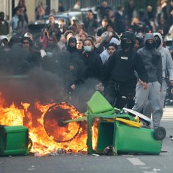 Un estudiante arroja basura a una hoguera mientras otros estudiantes manifestantes llevan a cabo un bloqueo cerca de la Place de la Nation, en París. Desde finales de septiembre, los estudiantes han protagonizado protestas frente a los centros educativos debido a diversas quejas, que van desde los horarios, el tamaño de las clases y la falta de profesores hasta el calor excesivo en las aulas durante las olas de calor de este año. Las protestas comenzaron en la región de Île-de-France, en los alrededores de París, pero se han extendido a otras ciudades de todo el país. | Foto:Thomas Samson / AFP
