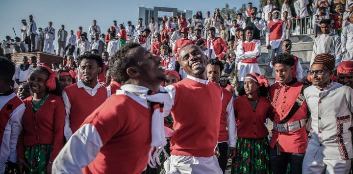 Jóvenes vestidos con chalecos rojos brillantes y atuendos tradicionales Oromo forman un círculo mientras bailan y cantan durante las celebraciones de Irreecha en Addis Abeba, Etiopía.