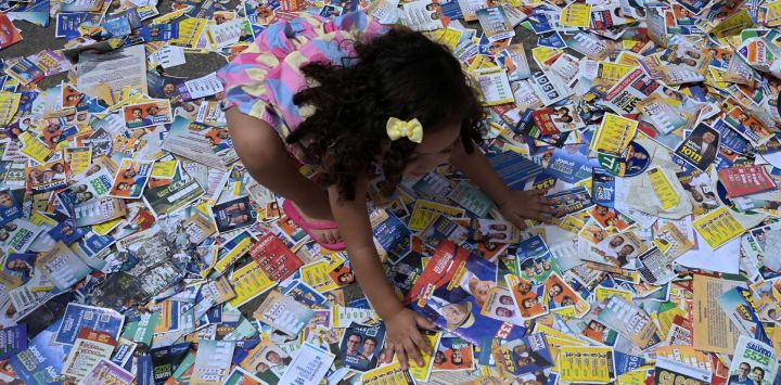 Una niña juega con folletos políticos en la favela Cidade de Deus, en el suroeste de Río de Janeiro (Brasil), el día de las elecciones presidenciales.