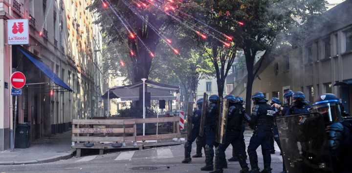 Agentes de la policía antidisturbios permanecen de pie mientras estallan fuegos artificiales sobre ellos durante una manifestación de estudiantes de secundaria junto a un sindicato de docentes en Lyon, en el centro-este de Francia.
