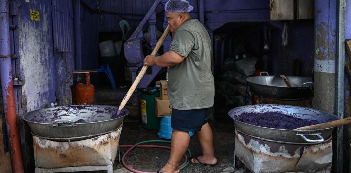 Esta fotografía muestra a un trabajador elaborando mermelada de ñame morado (ube halaya) en un establecimiento de Manila. El *ube* filipino se ha convertido en una sensación que marca tendencia desde Los Ángeles hasta Londres y Seúl; el intenso color púrpura de este humilde tubérculo genera largas filas frente a cafeterías y pastelerías, además de acumular millones de visualizaciones en las redes sociales.