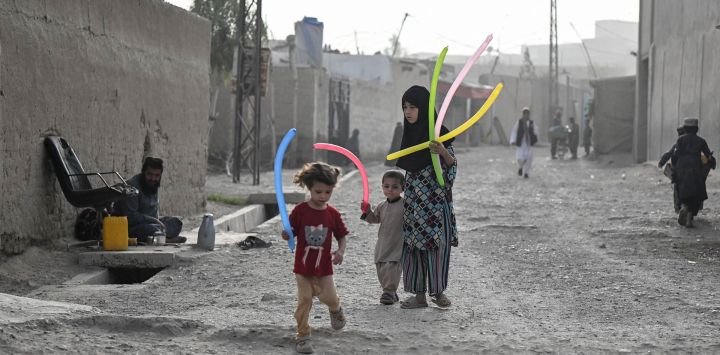 Una niña afgana y otros niños juegan con globos en una calle del distrito 7 de Kandahar, Afganistán.