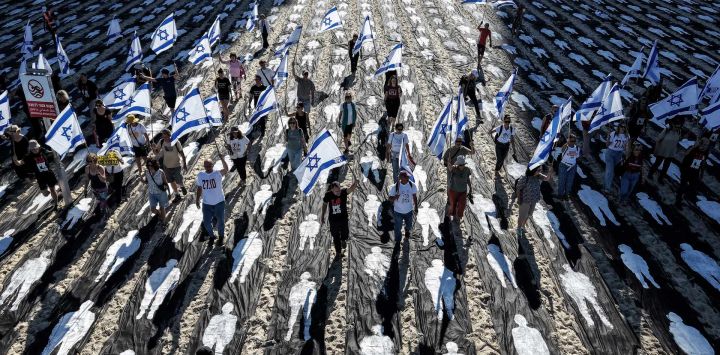 Una vista aérea muestra a personas ondeando banderas de Israel mientras permanecen en una instalación conmemorativa montada en la playa para marcar el tercer aniversario del ataque de Hamás a Israel.