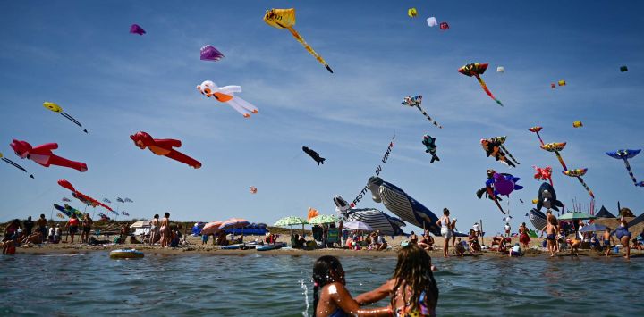 Unas cometas vuelan mientras la gente se baña durante el Festival del Viento en Portiragnes-Plage, en el sur de Francia.
