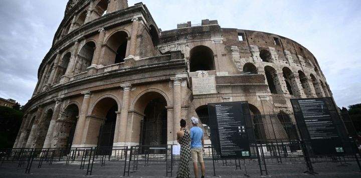 Unas personas permanecen frente al Coliseo Romano.