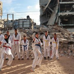 Jóvenes palestinos participan en una sesión de entrenamiento de taekwondo entre edificios destruidos en Nuseirat, en el centro de la Franja de Gaza. | Foto:Eyad Baba / AFP