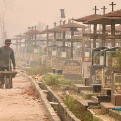 Un trabajador empuja una carretilla por un cementerio público cubierto por una densa capa de humo, causada por incendios forestales y de vegetación en Palangka Raya, provincia de Kalimantan Central. Indonesia ha sufrido grandes incendios forestales, mientras que el fenómeno meteorológico de calentamiento El Niño —que comenzó en junio y alcanzará su punto máximo a finales de este año— podría provocar más incendios en el sudeste asiático. | Foto:REINA / AFP