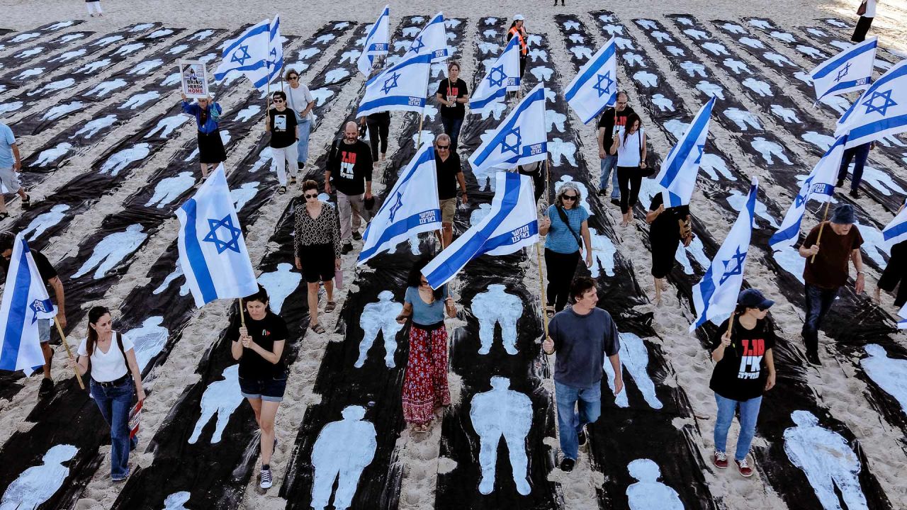 Una vista aérea muestra a personas portando banderas de Israel mientras caminan por una instalación conmemorativa montada en la playa de Tel Aviv para recordar el tercer aniversario del ataque de Hamás contra Israel. | Foto:JACK GUEZ / AFP