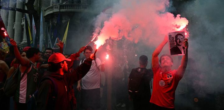 Estudiantes que apoyan al presidente de Brasil y candidato presidencial Luiz Inácio Lula da Silva para la segunda vuelta electoral encienden bengalas mientras sostienen una imagen del candidato derechista Flavio Bolsonaro caracterizado como Adolf Hitler, durante una marcha contra la extrema derecha en Río de Janeiro, Brasil. Lula da Silva, quien ha resurgido de las cenizas políticas en varias ocasiones, se dirige a una segunda vuelta electoral contra el senador derechista Flavio Bolsonaro el 25 de octubre, tras quedar sorpresivamente en segundo lugar en la primera ronda de votación.