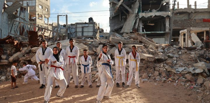 Jóvenes palestinos participan en una sesión de entrenamiento de taekwondo entre edificios destruidos en Nuseirat, en el centro de la Franja de Gaza.