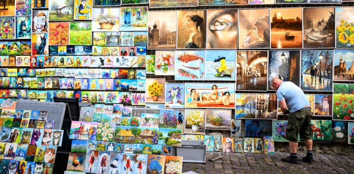 La fotografía muestra a un vendedor de arte organizando su puesto en una calle de Cracovia.