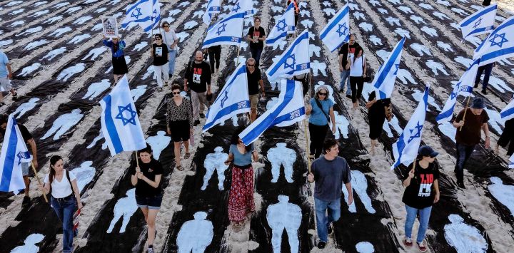 Una vista aérea muestra a personas portando banderas de Israel mientras caminan por una instalación conmemorativa montada en la playa de Tel Aviv para recordar el tercer aniversario del ataque de Hamás contra Israel.