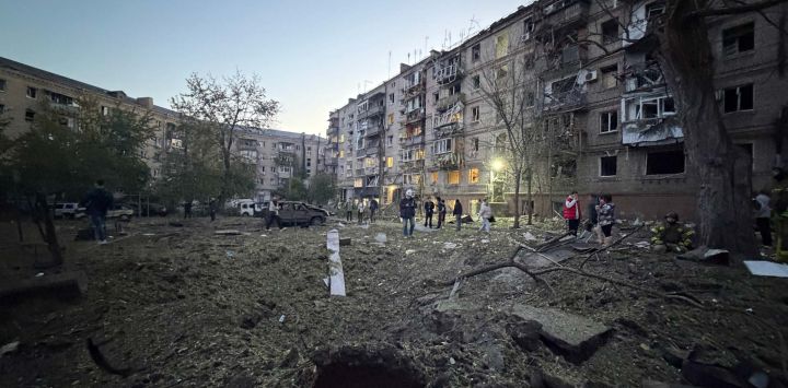Residentes locales permanecen frente a su edificio residencial, dañado tras un ataque ruso a Zaporiyia, en el contexto de la invasión rusa de Ucrania.