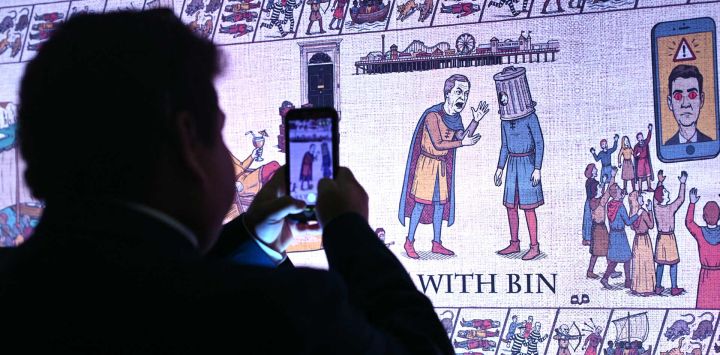 Un delegado examina el gran "Tapiz de Birmingham" —inspirado en el Tapiz de Bayeux y que se burla de los oponentes políticos— durante la primera jornada de la conferencia anual del Partido Conservador en Birmingham, en el centro de Inglaterra.