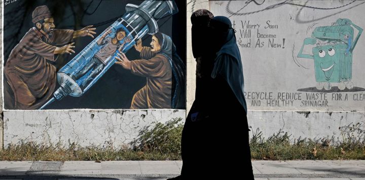 Unas mujeres pasan frente a un mural antidrogas en Srinagar, India.