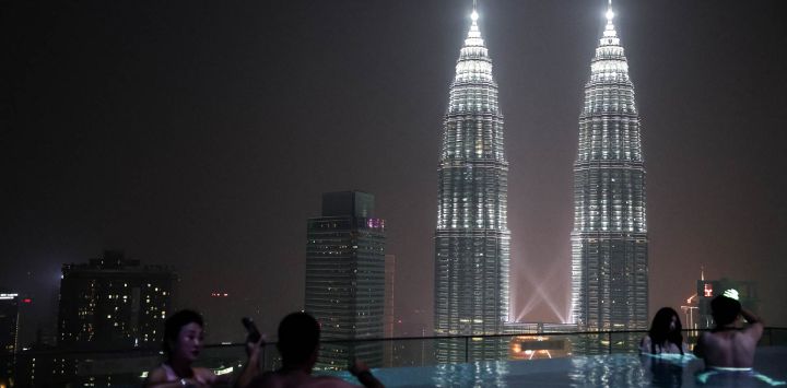 Unas personas se relajan en la piscina de la azotea de un hotel mientras se ven las Torres Petronas en Kuala Lumpur.