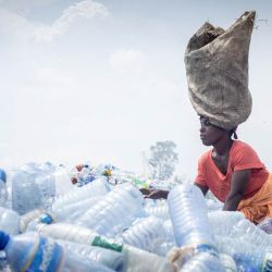 Kwizerimana Mateso lleva un saco sobre la cabeza mientras clasifica montones de botellas de plástico desechadas en el vertedero de Mubone, en el distrito de Buterere (Buyumbura). En el vertedero de Mubone —el principal depósito de residuos que abastece a Buyumbura, la capital comercial de Burundi—, cientos de mujeres pasan el día buscando fragmentos de carbón y materiales reciclables para venderlos en los mercados locales. Muchas de ellas son el único sustento de sus hogares y ganan unos 2.000 francos burundeses (aproximadamente 0,70 dólares) al día para mantener a sus familias, en un contexto donde la grave inflación y la escasez nacional de combustible impulsan la demanda de energía doméstica más económica. | Foto:Herve Shabani / AFP