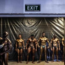 Los competidores aguardan entre bastidores mientras se preparan para salir al escenario durante el Campeonato Internacional de Fitness Body Fuel 2026, celebrado en Nairobi. El campeonato reunió a atletas de toda África y otras regiones, poniendo de manifiesto la creciente popularidad del culturismo y el fitness competitivo en el continente. | Foto:LUIS TATO / AFP