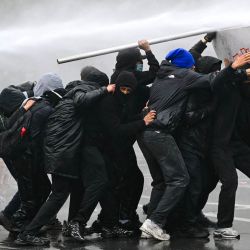Un cañón de agua rocía a los manifestantes durante una protesta sindical contra las medidas presupuestarias del Gobierno federal, cerca de la estación de tren Bruselas-Sur. Trabajadores belgas y estudiantes de secundaria salieron a las calles ese mismo día para participar en una nueva huelga nacional contra las medidas de austeridad gubernamentales. La manifestación, que se esperaba congregara a miles de personas en Bruselas, se produce en un clima de gran tensión, después de las protestas estudiantiles —inspiradas en las que tienen lugar en Francia— derivaran en actos violentos. | Foto:NICOLAS TUCAT / AFP