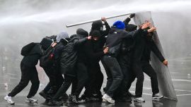 Un cañón de agua rocía a los manifestantes durante una protesta sindical contra las medidas presupuestarias del Gobierno federal, cerca de la estación de tren Bruselas-Sur. Trabajadores belgas y estudiantes de secundaria salieron a las calles ese mismo día para participar en una nueva huelga nacional contra las medidas de austeridad gubernamentales. La manifestación, que se esperaba congregara a miles de personas en Bruselas, se produce en un clima de gran tensión, después de las protestas estudiantiles —inspiradas en las que tienen lugar en Francia— derivaran en actos violentos.