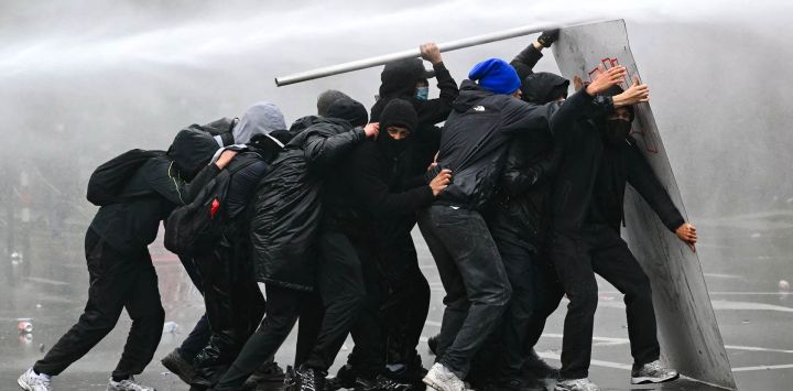 Un cañón de agua rocía a los manifestantes durante una protesta sindical contra las medidas presupuestarias del Gobierno federal, cerca de la estación de tren Bruselas-Sur. Trabajadores belgas y estudiantes de secundaria salieron a las calles ese mismo día para participar en una nueva huelga nacional contra las medidas de austeridad gubernamentales. La manifestación, que se esperaba congregara a miles de personas en Bruselas, se produce en un clima de gran tensión, después de las protestas estudiantiles —inspiradas en las que tienen lugar en Francia— derivaran en actos violentos.