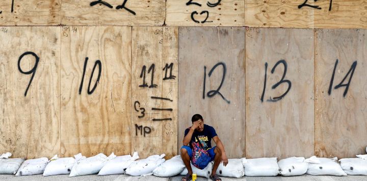 Un hombre está sentado sobre sacos de arena ante la llegada del huracán Simon en Puerto Vallarta, estado de Jalisco, México. El huracán Simon se intensificó hasta convertirse en una poderosa tormenta de categoría 4 mientras avanzaba hacia la costa occidental de México.