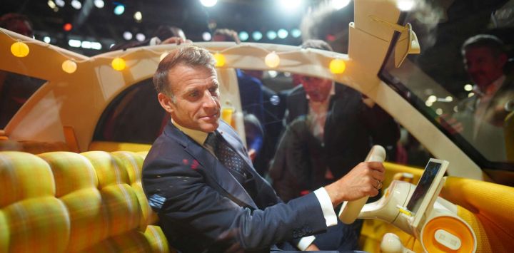 El presidente de Francia, Emmanuel Macron, sentado en el interior de un Citroën 2 CV durante el Salón Internacional del Automóvil de París, en la Porte de Versailles de París.