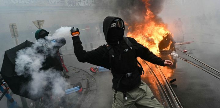 Un manifestante devuelve una granada de gas lacrimógeno durante una protesta sindical contra las medidas presupuestarias del Gobierno federal, cerca de la estación de tren Bruselas-Sur, en Bruselas. Trabajadores belgas y estudiantes de secundaria se unieron para salir a las calles en una nueva huelga nacional contra las medidas de austeridad del Gobierno. La manifestación, que se prevé congregue a miles de personas en Bruselas, tiene lugar en un clima de gran tensión, después de que esta semana las protestas estudiantiles —inspiradas en las que se desarrollan en Francia— derivaran en actos violentos.