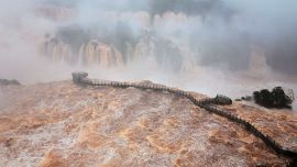 Una vista general muestra la pasarela para visitantes en las cataratas del Iguazú, situada sobre una fuerte corriente y vista desde el lado brasileño de la triple frontera entre Brasil, Argentina y Paraguay —en la ciudad de Foz do Iguaçu, estado de Paraná, Brasil. Las autoridades cerraron temporalmente el acceso turístico a las cataratas del Iguazú debido a la crecida del río homónimo, al tiempo que se registraron aumentos en el caudal de los ríos Paraná y Uruguay como consecuencia de las lluvias asociadas al fenómeno de El Niño.
