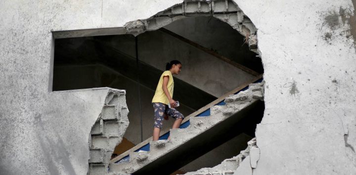 Una mujer palestina es vista a través de un gran boquete mientras sube una escalera para inspeccionar una vivienda alcanzada por ataques aéreos israelíes —tras la advertencia del ejército israelí a los residentes para que evacuaran la noche anterior— en Al-Zawayda, en el centro de la Franja de Gaza. Un año después de que el presidente de Estados Unidos declarara el fin de la guerra en Gaza, pocas de las promesas a largo plazo del alto el fuego se han materializado; si bien Israel ha reducido la intensidad de sus ataques, ha seguido bombardeando Gaza casi a diario. Según el Ministerio de Salud de Gaza, los ataques han causado la muerte de unos 1.450 palestinos desde el inicio del alto el fuego.